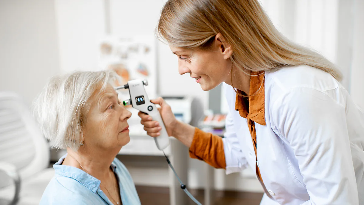 An optometrist measuring an older woman's eye pressure with a handheld tonometer
