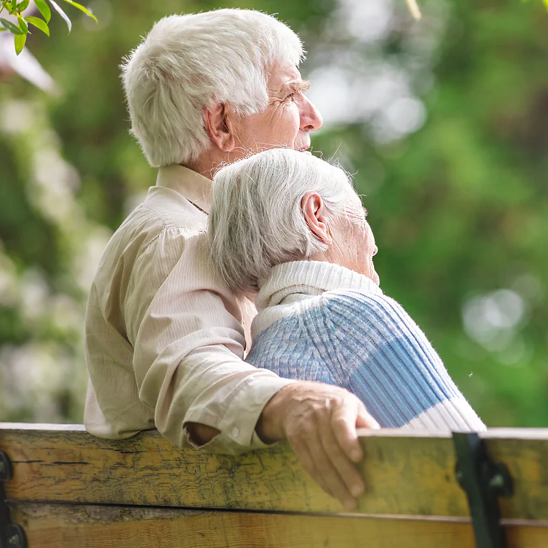 An older couple sitting together on a park bench