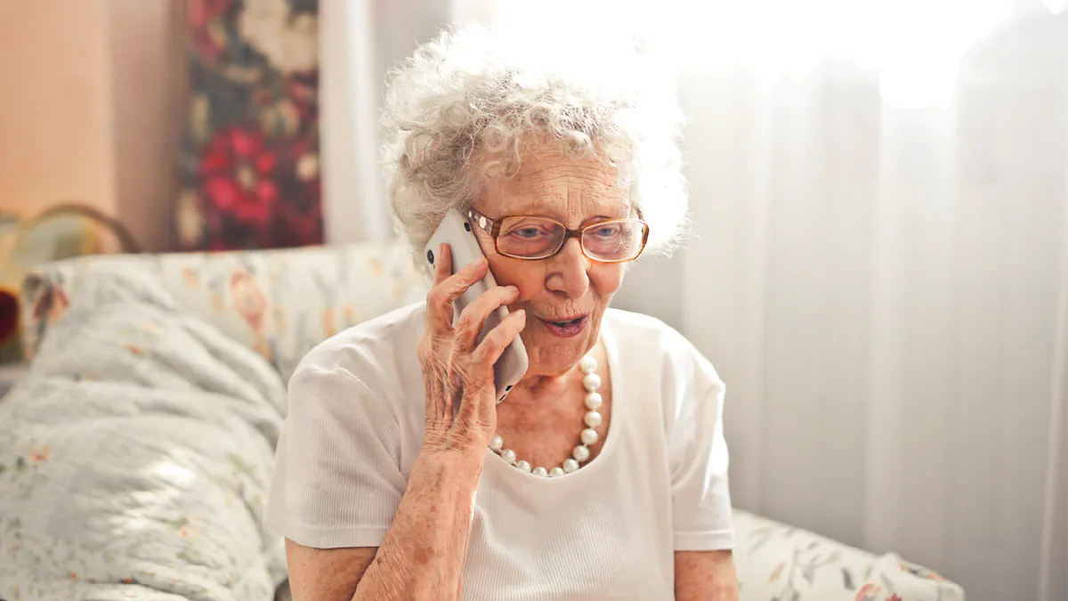 A smiling older woman chatting on the phone at home