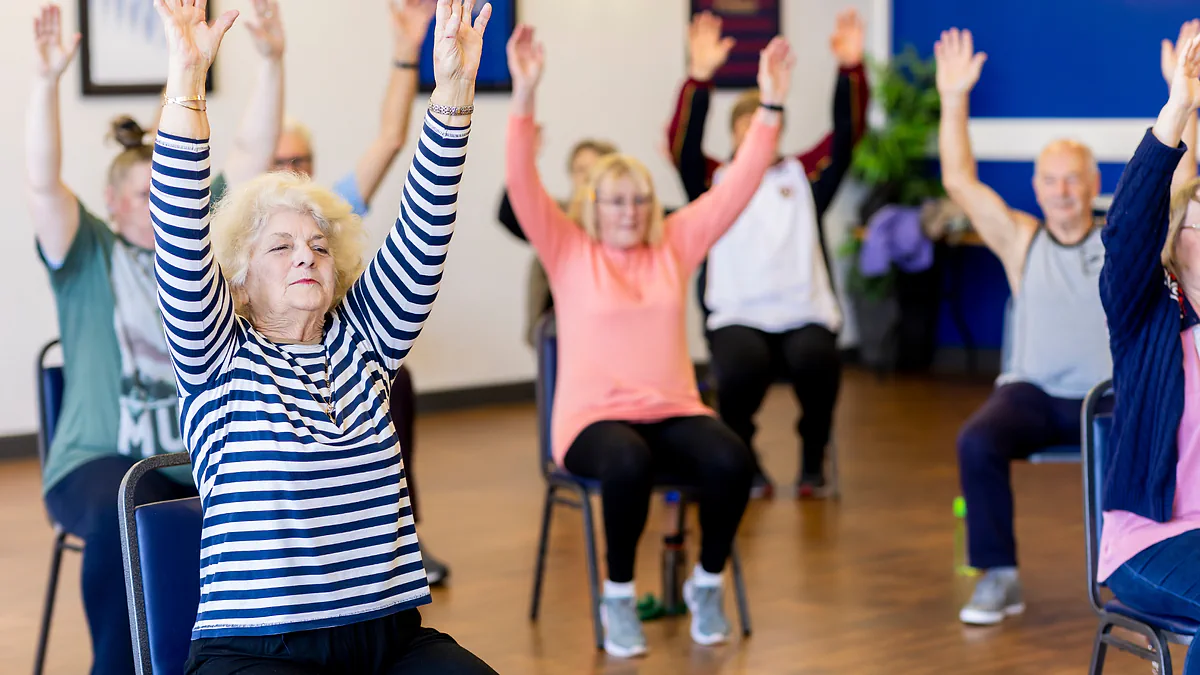 Older adults raising their arms in a seated exercise class