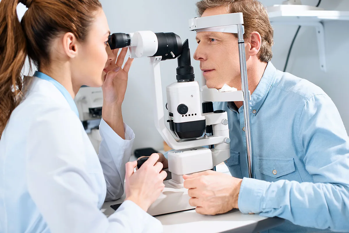 An eye specialist examining a man's eyes at a slit lamp