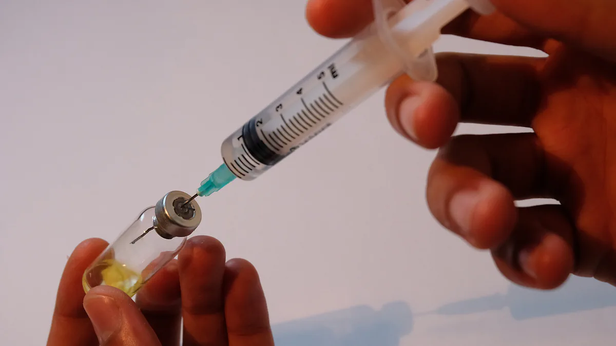 A syringe drawing medicine from a small vial