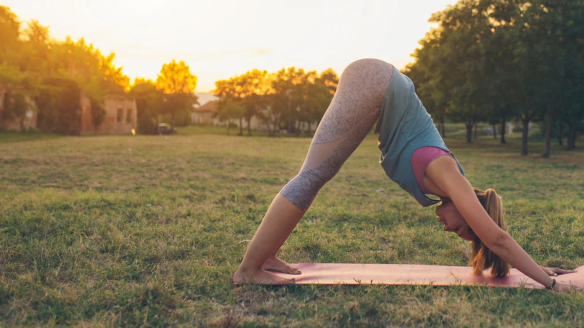 A woman doing yoga in a park at sunset