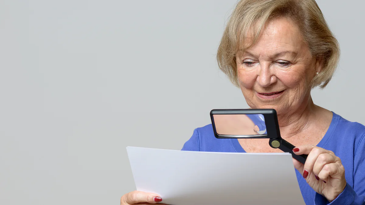 A woman reading a document through a handheld magnifier